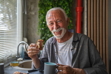 Happy senior man enjoying breakfast in modern kitchen