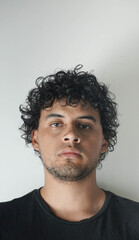 Fototapeta premium Latino boy with curly hair on a white background and a black t-shirt