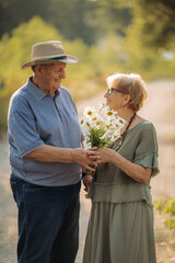 An elderly man gives his wife a bouquet of flowers on their wedding anniversary