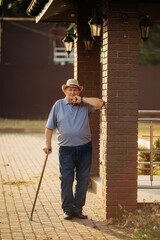 Grandfather in a hat. Portrait of a very old Caucasian man. Portrait: elderly, lonely, elderly, with many wrinkles on his face. Close-up of a thoughtful old man standing alone outdoors.