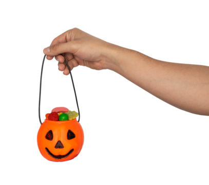 Hand holding a halloween pumpkin bucket filled with colorful gummy candies isolated on transparent background.  Trick or treat celebration and spooky festive designs. 