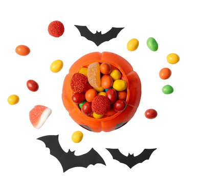 Top view of a pumpkin jack o lantern bucket filled with assorted colorful candies surrounded by bats and sweets on a transparent background for halloween celebrations.