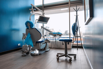 Fototapeta premium Contemporary dental chair setup in a clinic with tools and monitor near large window. Concept of modern dentistry, patient care, and clean medical environment.