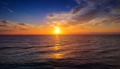 Fototapeta premium spectacular sunset over the ocean a breathtaking view of the sun dipping below the horizon casting a warm golden glow on the tranquil sea the serene scene is a perfect blend of