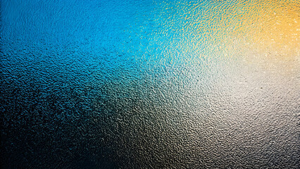 Abstract Close-Up of Textured Frosted Glass with Diagonal Gradient of Blue, Yellow, and Dark Tones  
