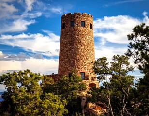 Stone tower amidst a landscape of trees and clouds