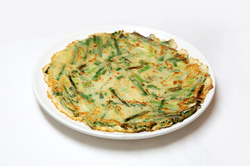 High resolution photo of Korean vegetable pancake, pajeon, served on white background. A traditional Korean dish made with green onions, vegetables, and crispy batter.