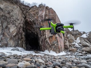 Obraz premium Green drone flying near rocky coast in winter