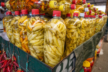 Jarred pickled yellow peppers for sale at an outdoor market.