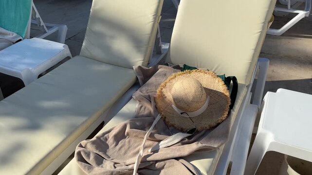 Two sun loungers by the pool or on the beach. Towel and a straw hat on a chaise longue