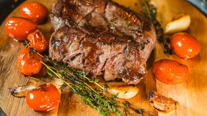 Perfectly cooked medium rare ribeye steak, juicy, on a wooden board with fresh thyme and roasted garlic. Top view food photography for menus and recipes.