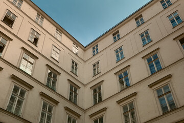 Up-close view of a white classical building corner in Vienna, showcasing detailed architecture against a clear blue sky.