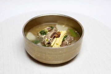 High resolution photo of Korean galbitang, beef short rib soup served in hot broth with vegetables on white background. A healthy and traditional Korean cuisine dish.