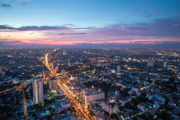 Cityscape at dusk.  Aerial view of a sprawling metropolis at sunset.  Vibrant colors,  urban lights, and highways