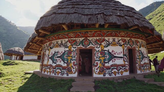 Indigenous kogi people are entering and exiting a traditional circular hut with colorful decorations and thatched roof in the mountains of the sierra nevada de santa marta, colombia