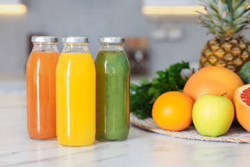 Tasty juices in glass bottles and fresh ingredients on white marble table indoors, closeup