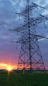 Powerful electricity pylons against a vibrant sunset symbolize sustainable energy infrastructure, blending industrial technology with natural beauty.