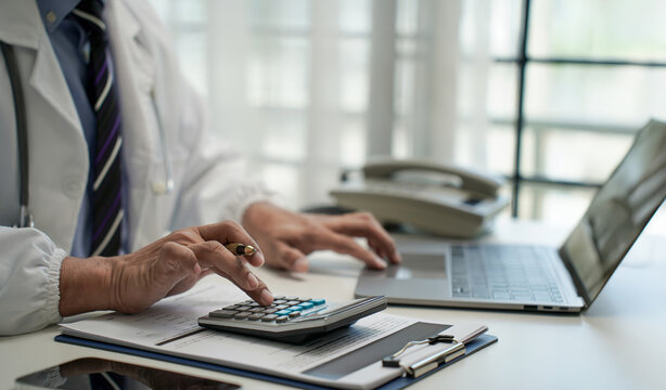 Doctor working with calculator and laptop in office, concept of medical finance, healthcare costs, hospital administration, and health insurance management.