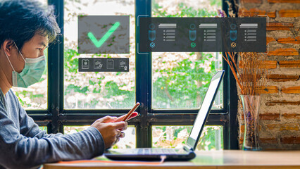 An Asian man in a face mask uses his smartphone to complete an online verification process. Digital icons of checklists and approved profiles float over his laptop, symbolizing successful validation.