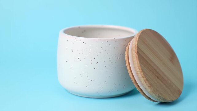 White Speckled Ceramic Jar with Bamboo Lid on Light Blue