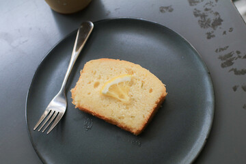 Slice Lemon pound cake on black plate. homemade dessert. Delicious breakfast, traditional English tea time.