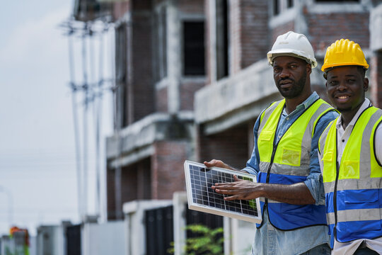 An experienced engineer teaches an apprentice about solar panel installation on a construction site. A concept for green building, renewable energy, and sustainable construction.