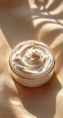 Creamy lotion in a round container, bathed in warm sunlight, casting shadows
