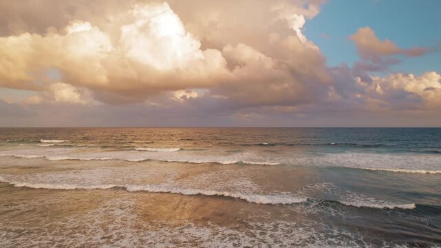 Sea waves rolling in under dramatic clouds during tropical sunset
