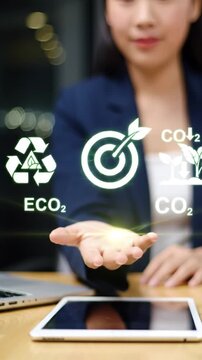 Businesswoman presents glowing holographic eco-friendly icons of recycling, sustainable goals, and CO2 reduction for environmental initiatives.