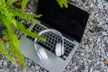 Close up on modern laptop with blank screen standing on surrounded by wireless headphones