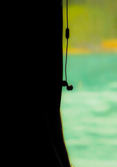 A Detailed Close-up Silhouette of a Person's Side View with Wired Earphones Hanging Down, an Image that Powerfully Represents a Moment of Personal Relaxation