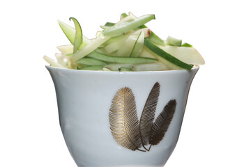 A Detailed Close-up, Eye-Level Shot of an Elegant White Bowl with Gold Feather Patterns, Filled with a Fresh and Appetizing Pile of Sliced Green and White Vegetables or Fruit