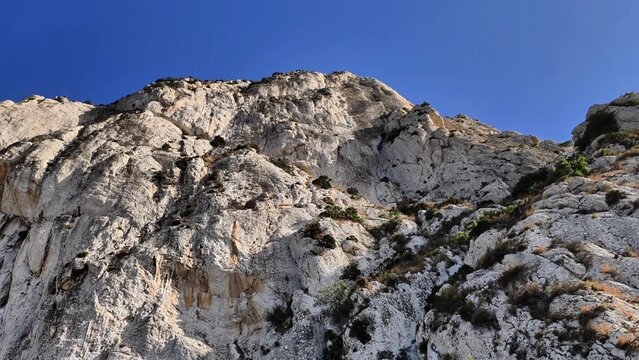 The Majestic Rocky Cliff Stands Tall and Proud Under a Clear and Bright Blue Sky Above Us