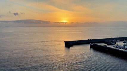 A Stunning Sunset Over the Calm Ocean, Complete with a Charming Pier, Offers Unmatched Beauty