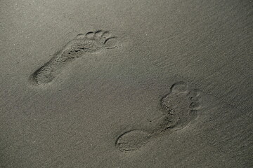 Two footprints on wet grey sand
