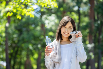 Fototapeta premium タオルで汗を拭って水分補給する女性