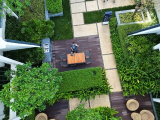 This photo showcases a beautifully designed outdoor patio garden, blending natural elegance with modern comfort. A central wooden dining table with four chairs invites gatherings, while surrounding gr