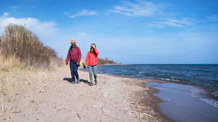 A weekend off, vacation, or date. Two travelers are wandering along the beach with beer bottles in their hands. Two people are walking along the seashore