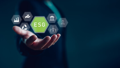 Businessman holding ESG icons including sustainability, renewable energy, recycling, governance,...