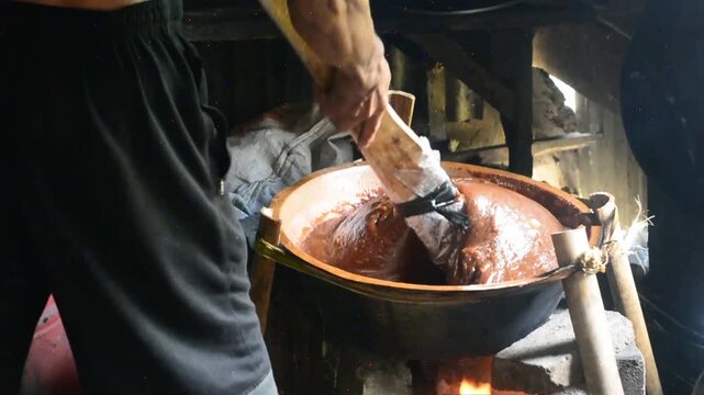 Making dodol in a large container, also called kalu dodol in sri lanka, dark sweet candy, made from coconut milk, jaggery and rice flour, sticky, thick, sweet toffee, closeup