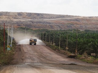 A heavy duty water tanker, with very large dimensions, is sprinkling water on the road to prevent dust.