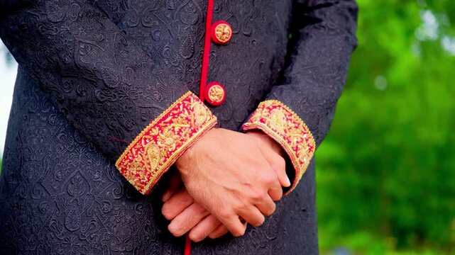 Groom Dressed in traditional Indian or Pakistan black suit with red color Elements . Asian wedding. Close up footage