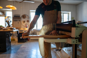 Focused carpenter operating band saw machine, wearing earmuffs for safety in workshop. Woodwork preparation, client delivery, furniture handmade, power tools, skilled craftsmanship in carpentry studio