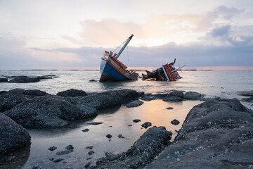 Old wrecked fishing boat at twilight sky, shore of Ang Sila Village, Chonburi Province of thailand suite for concept of sea ​​travel, shipping, natural disasters, sea travel safety and insurance.
