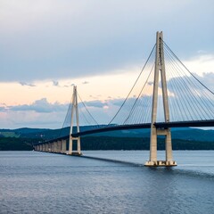Obraz premium A long cable-stayed bridge spans a calm body of water under a pale sky