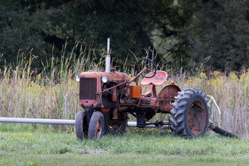 Vintage red agricultural tractor abandoned in a rural grassy field