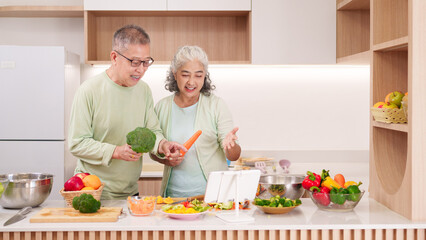 Asian elderly couple preparing healthy vegetables cooking together modern kitchen following digital tablet recipe home for healthy lifestyle