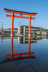 Gordijnen Torii Gates Traditional red torii gate reflected in calm water near urban buildings at Fujinomiya, Shizuoka, Japan,  © Kitinut
