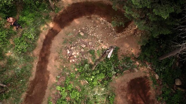 Mountain biker riding around dirt berm in forest dirt jumps