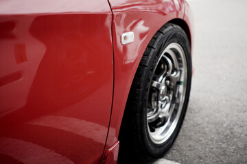 Fototapeta premium Close-Up Detail of Red Car with Chrome Alloy Wheel